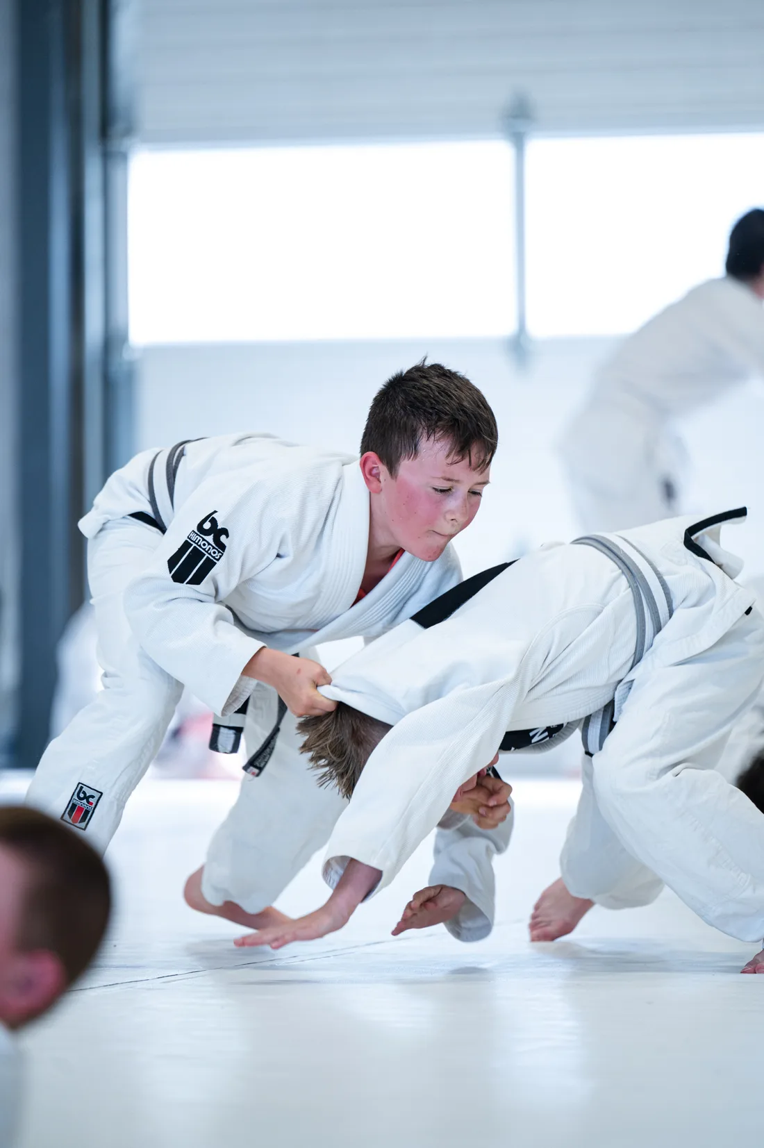 Two children practising a Jiu-Jitsu takedown under supervision at ALAVANCA Shawnessy in Calgary