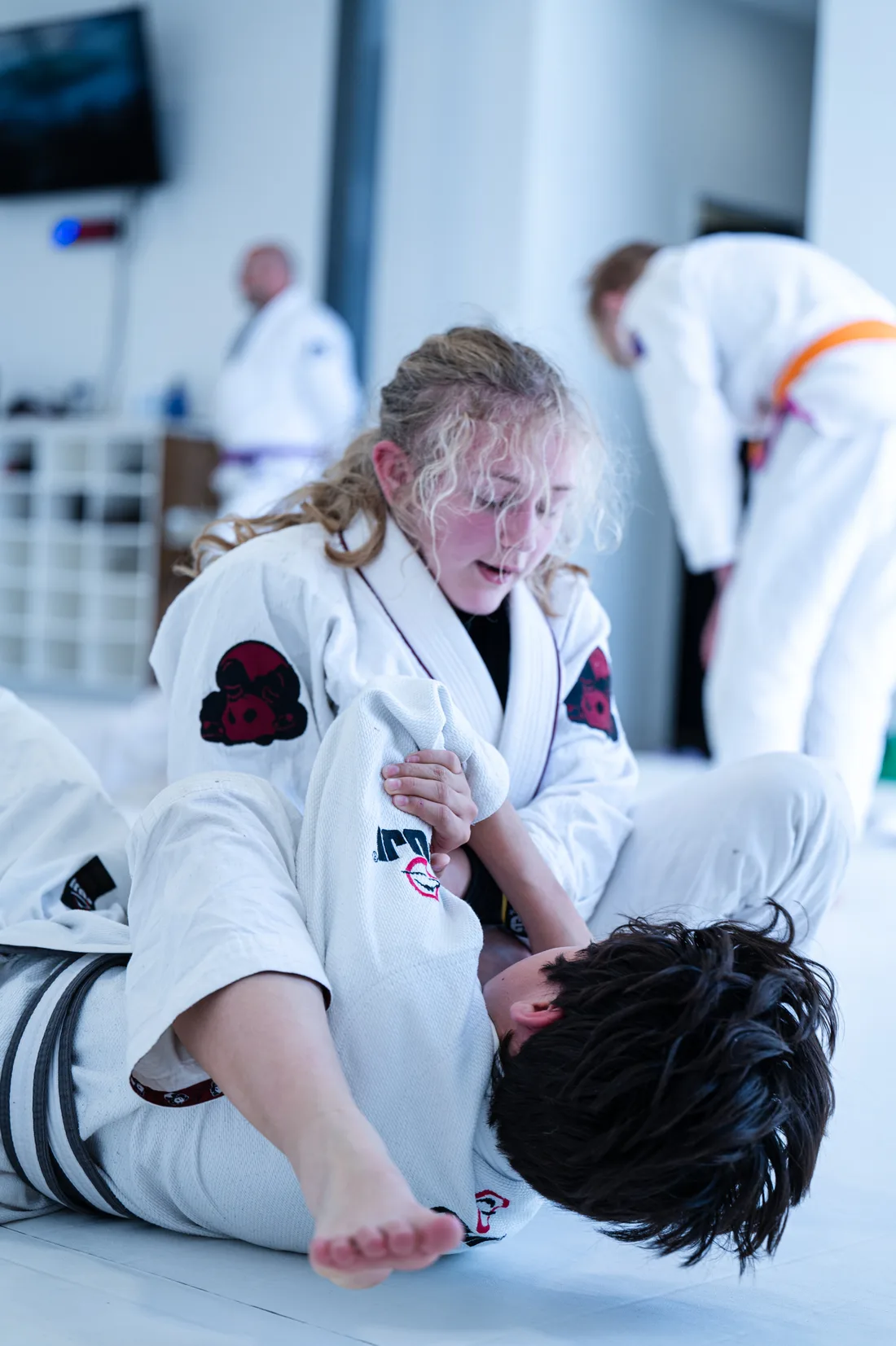 A young Alavanca Shawnessy student practising a guard technique with a partner during a kids Jiu-Jitsu class in Calgary